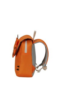 La mochila naranja presenta una tela texturizada, un bolsillo lateral con cremallera y cintas de malla para mayor comodidad, con un elemento de diseño divertido en la parte frontal.