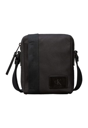 Malá černá kabelka přes rameno s nastavitelným popruhem, vertikálním textilním detailem, zapínáním na zip a malou logovou nášivkou na přední straně.