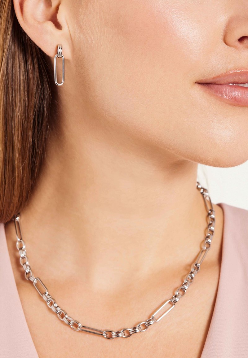 Zilveren ketting met verlengde schakels en bijpassende ovale oorbellen. Glad metalen afwerking met een slank ontwerp.