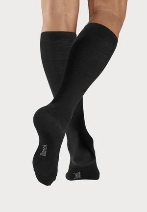 Schwarze knielange Socken aus einem glatten, dehnbaren Material, mit gerippter Textur und Logodetail im Knöchelbereich.