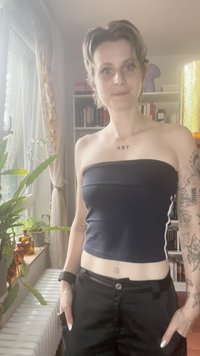Top scurt negru cu decolteu drept și dungi laterale albastre deschise, asociat cu pantaloni negri cu talie înaltă. Accesoriile includ un inel și o brățară.