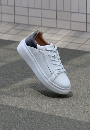 Hvide lædersneakers med en struktureret grå hæl, guldaccent og flade snørebånd. Har små dekorative nitter langs siden.