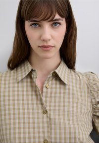 Skjorte med knapper foran i beige og lyseblåt ternet mønster, med klassisk krave og puffede ærmer. Glat bomuldstof.