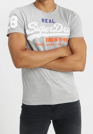 Grå bomuld T-shirt med ribbet rund halsudskæring, korte ærmer og trykte grafik i hvid, blå og orange, kombineret med mørke jeans.