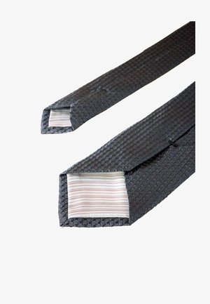 Tumedatehallikus hall sidematerjal, millel on kootud muster. Sees on kerge kangas peenikeste, värviliste triipudega. Otstes on teravad nurgad.