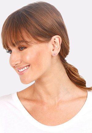 Pendientes de plata, forma redonda, superficie suave, acabado pulido. El modelo tiene el cabello castaño medio, lleva una blusa clara, estilo minimalista.