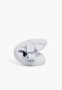 Białe płócienne buty z zaokrąglonym noskiem i teksturowaną gumową podeszwą. Posiadają metalową klamrę i minimalistyczny design.