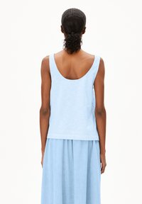 Light blue tank top with white horizontal stripes, scoop back design, made from soft fabric. Paired with a matching light blue skirt.
