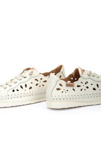 Creme lædersneakers med udskåret blomsterdesign, prydet med beige snørebånd og dekorativ syning langs sålen. Lysebrunt foder synligt indeni.