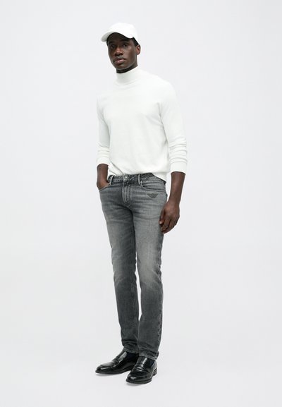 Λευκό πουλόβερ με ζιβάγκο, γκρι τζιν παντελόνι, μαύρες εσπαντρίγιες και λευκό καπέλο. Ουδέτερα χρώματα, εφαρμοστή σχεδίαση και διακριτές υφές.