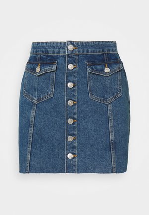 Tummansininen A-linjainen farkkuhame, jossa on viisi etupainiketta, kaksi etutaskua ja näkyvät ompeleet. Lyhyt pituus, jämäkkä istuvuus.