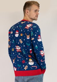 Blue knit sweater with festive designs featuring Santa, snowmen, reindeer, and Christmas trees. Red cuffs and waistband; textured pattern.