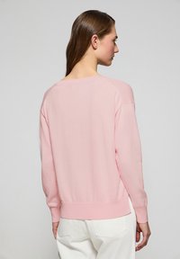 Ljusrosa långärmad tröja med en avslappnad passform, ribbad nederkant och muddar, samt en vid båthalsringning, tillverkad av mjukt och slätt material.