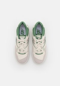 Beige and green New Balance 550 sneakers with laces, viewed from above on a white background.