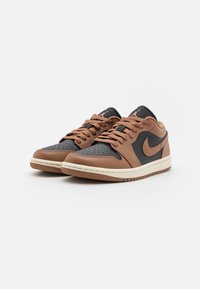 Smeđe i crne kožne tenisice s teksturiranim završetkom, sa vezicama, perforiranim prstom i bijelom srednjom potplatom. Nike logo na strani.