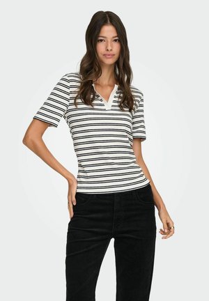 Stribet kortærmet top i hvid og sort med en rund halsudskæring. Stoffet ser glat og tætsiddende ud, parret med sorte kordfløjspants.