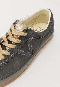 Baskets Vans en daim gris avec des lacets beiges, des coutures blanches et une semelle gomme translucide montrant la doublure intérieure couleur crème.