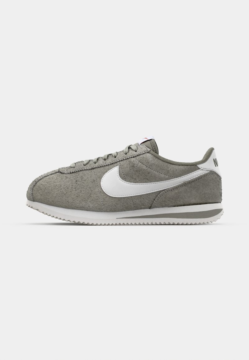 Sneaker in suede grigio con dettagli bianchi, dotati di punta arrotondata, superficie testurizzata e un classico design con lacci, completo di suola rigata.
