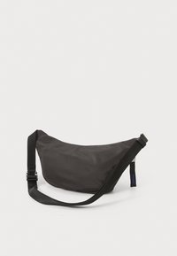 Marsupio in nylon nero con design curvo, tracolla regolabile e etichetta logo laterale. Texture liscia e stile minimalista.