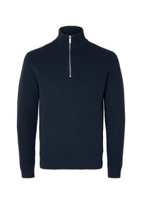 Námořnicky modrý pletený pulovr s vysokým límcem a polovičním zipem. Má žebrované manžety a lem, které poskytují texturovaný, ležérní vzhled.