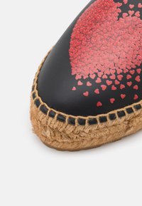 Chaussure espadrille noire vue de face avec semelle en jute naturel et décoration en forme de groupe de cœurs rouges sur la zone des orteils