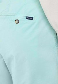 Pantalones cortos de color azul claro, confeccionados con una tela suave, con un cierre de botón y una pequeña etiqueta en color marino con la inscripción "Féminable" cosida en el bolsillo.