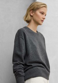 Grau gestrickter Pullover mit Rundhalsausschnitt sowie gerippten Bündchen und Säumen. Das Design zeichnet sich durch eine lockere Passform und eine weiche Textur aus, die sich gut zum Schichten eignet.