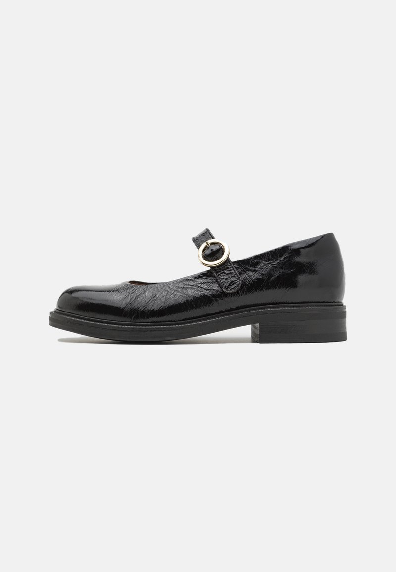Chaussure Mary Jane en cuir verni noir avec bout arrondi, petit talon bloc et bride ajustable avec boucle dorée sur fond blanc.