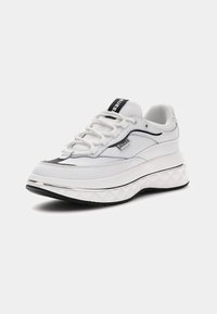 Sneaker bianca con tomaia in pelle testurizzata, dettagli neri, suola spessa e testurizzata, e forma arrotondata. Presenta lacci e logo sulla linguetta.