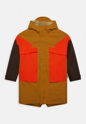 Brązowa i pomarańczowa wodoodporna kurtka z kapturem, z dużymi przednimi kieszeniami oraz kontrastującymi blokami kolorów na ramionach i rękawach.