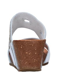 Sandalo bianco con tacco in sughero, con apertura sul retro e cinturino regolabile. Presenta dettagli metallici e una superficie liscia sul materiale superiore.