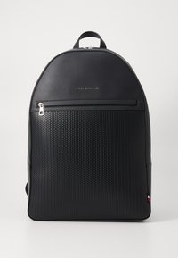 Zaino nero con una parte superiore liscia e una parte inferiore testurizzata con un motivo esagonale. Include una tasca frontale con zip e un dettaglio del logo.