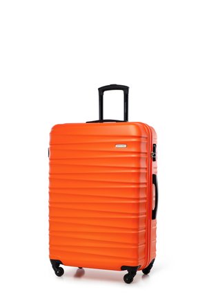Twarda pomarańczowa walizka z żebrowaną teksturą, czarną wysuwaną rączką, boczną rączką oraz czterema czarnymi kółkami obrotowymi, które zapewniają łatwe poruszanie się.