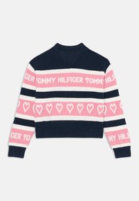 Heklet genser med et marineblått, rosa og hvitt stripemønster. Har teksten "TOMMY HILFIGER" og hjerte-motiver. Ribbet krage og mansjetter.