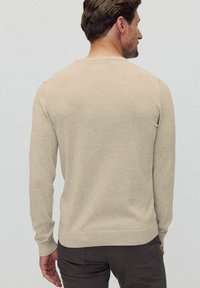 Beige långärmad tröja i mjukt material med rundad halsringning och ribbade ärmslut, med en enkel baksida.