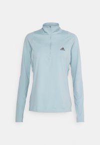 Helles, blaues, langärmliges Sportoberteil mit einem Viertel-Reißverschlusskragen, das über ein schwarzes Adidas-Logo auf der linken Brust und strukturierte Seiteneinsätze verfügt.