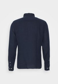 Granatowa koszula z długim rękawem, zapinana na guziki, pokazana z tyłu z kołnierzykiem i zapiętymi mankietami na jednolitym jasnym tle.