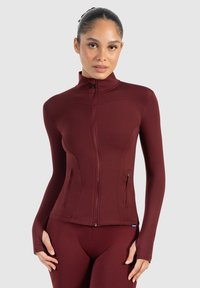Bordeaux sportieve zip-up jack, slim fit ontwerp, lange mouwen met duimopeningen, twee zijzakken, zachte textuur en hoge kraag.