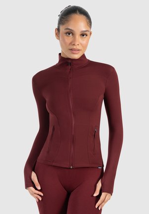 Bordeaux sportieve zip-up jack, slim fit ontwerp, lange mouwen met duimopeningen, twee zijzakken, zachte textuur en hoge kraag.