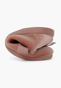 Zapatilla de terciopelo en un suave y polvoriento tono rosa, con punta redondeada y suela de goma flexible; cuenta con una tira de tela para facilitar su uso.