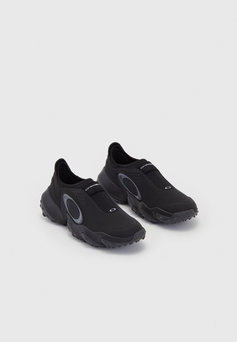 Juodos slip-on sneaker'iai su tekstūruotu paviršiumi ir guma padu. Ypatybės: pilkas apvalus akcentas ir elastinga juosta ant pėdos vidurinės dalies, užtikrinanti patogią prigludimą.