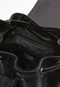 Czarna torebka o fakturze skóry, zamykana na troczek, wyposażona w wewnętrzną kieszeń na zamek oraz oznaczenie marki. Gładka podszycie wnętrza, bez zewnętrznych detali.