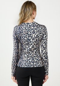 Bluzka z długim rękawem w beżowo-granatowy wzór w panterkę, wykonana z elastycznego materiału, dopasowana, z okrągłym dekoltem.