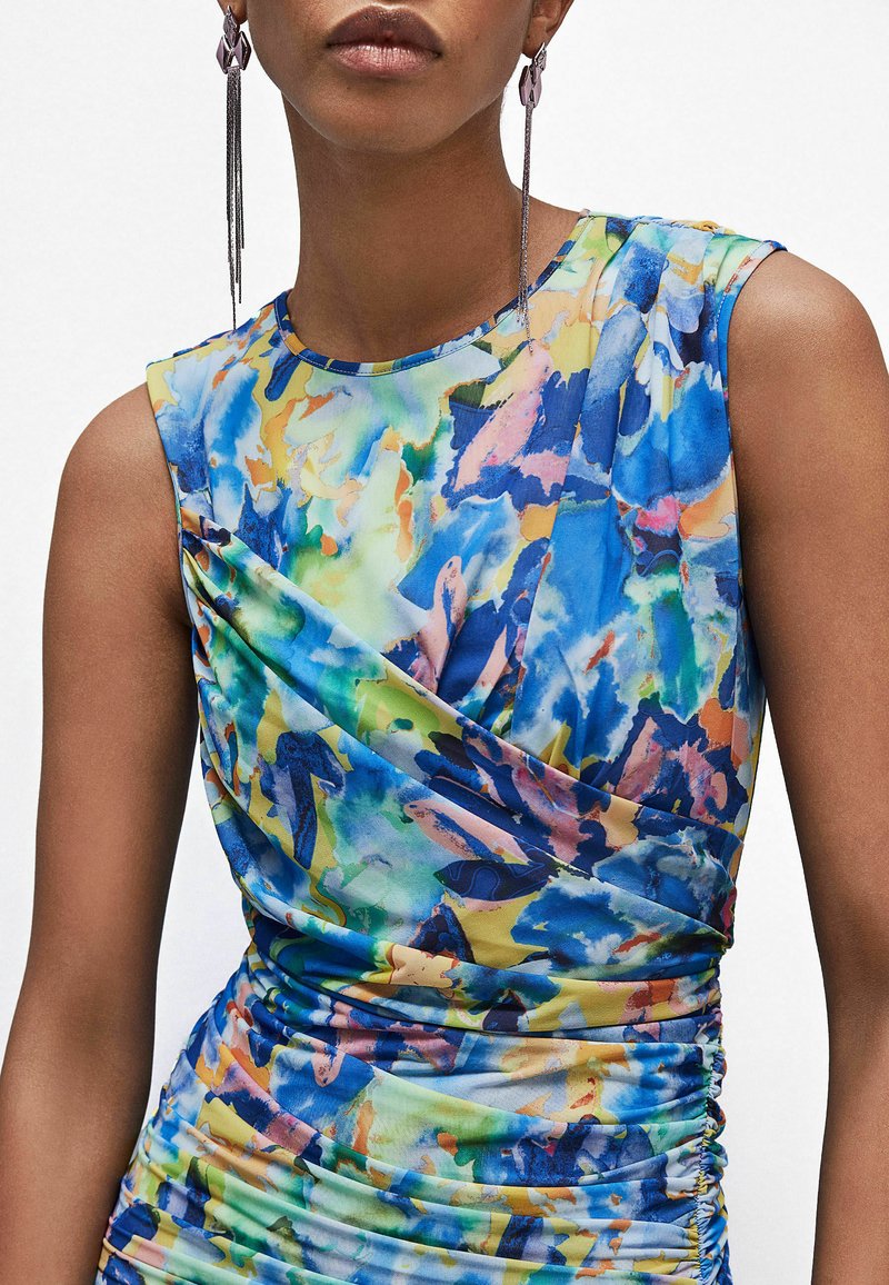 Sukienka bez rękawów z wielokolorowym, abstrakcyjnym wzorem w odcieniach niebieskiego, zielonego, żółtego i różowego; marszczenia po bokach nadają teksturę.