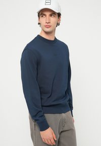 Tmavomodrá mikina s dlhým rukávom z bavlnenej zmesi, s okrúhlym výstrihom, rebrovanými manžetami a subtílnym logom na hrudi.
