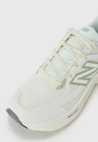 Lightweight running shoe with a breathable mesh upper in white and light green accents, featuring a textured pattern and cushioned sole.