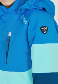 Blaue und hellblaue zip-up Jacke mit Kapuze, ausgestattet mit einer vorderen Reißverschlusstasche und einem "ZIGZAG" Logo-Patch auf der linken Schulter.