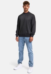 Mørkegrå fleece sweatshirt med langeærmer, ribbede manchetter og rund halsudskæring, sammen med lyseblå jeans og hvide sneakers.