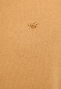 Honey-colored sweater with a textured knit finish, featuring an embroidered silhouette of a horse in a tonal thread on the left side.