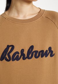 Brown cotton sweatshirt featuring a navy blue embroidered "Barbour" logo on the front. The neckline is ribbed, with raglan sleeves.